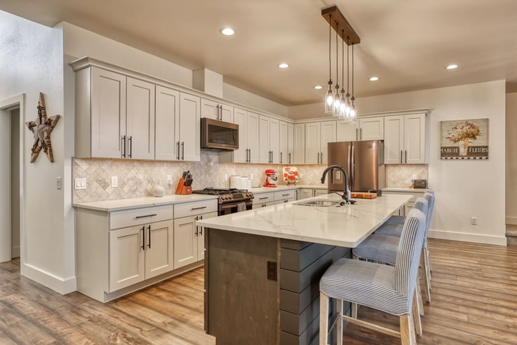 White custom kitchen design with island and seating beneath pendant light fixture