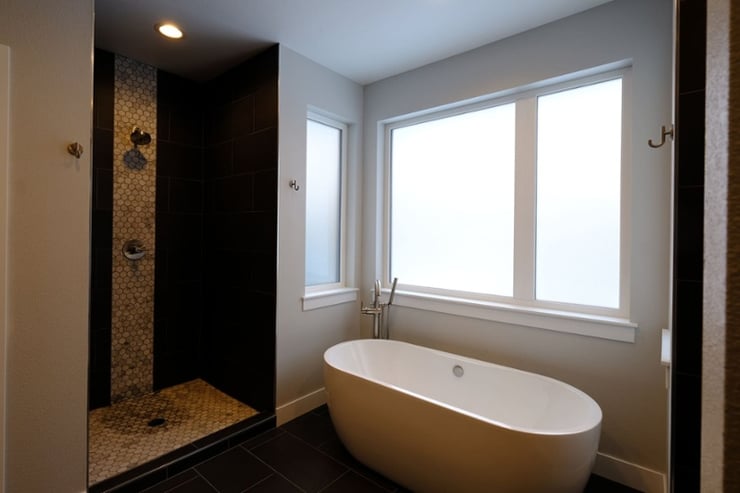 Walk-in shower and white soaking tub by window in bathroom