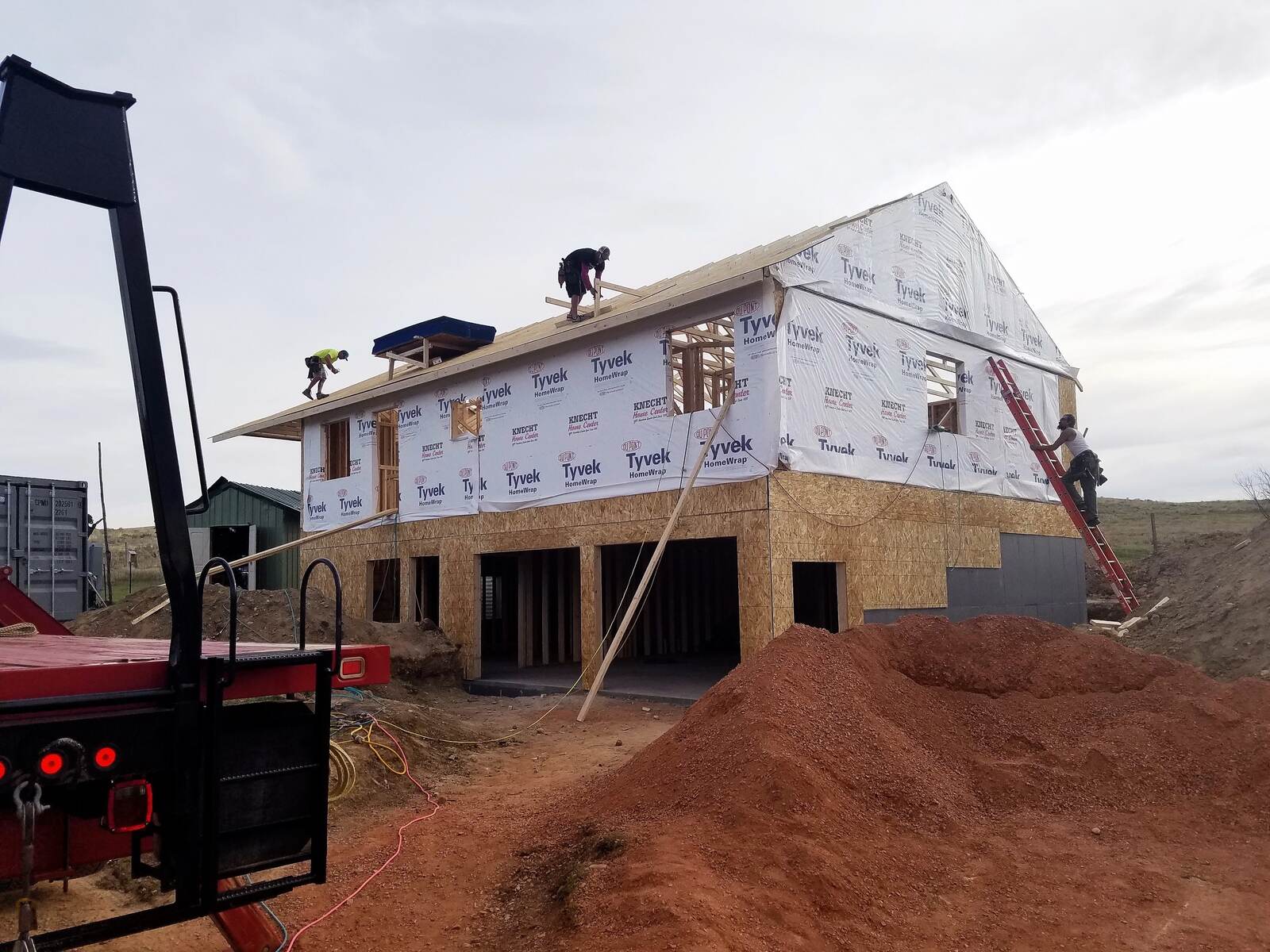 framing exterior with roofers on top for new custom home in wyoming