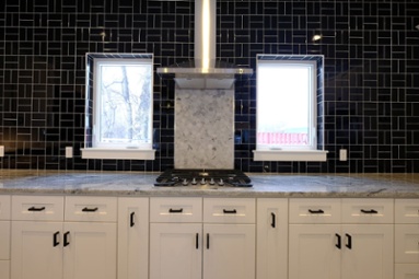 black-mosaic-tile-backsplash-behind-white-shaker-cabinets-and-cooktop-in-kitchen-1
