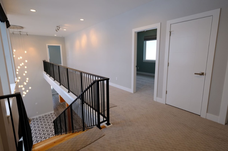 second-story-hallway-of-custom-home-with-black-railing-along-steps-1