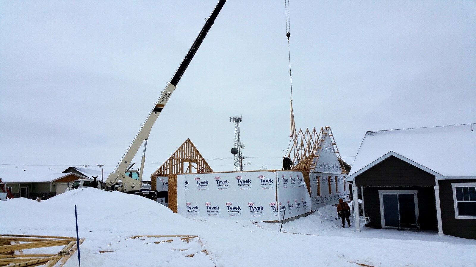 building a custom home framing roof with crane in snow in wyoming