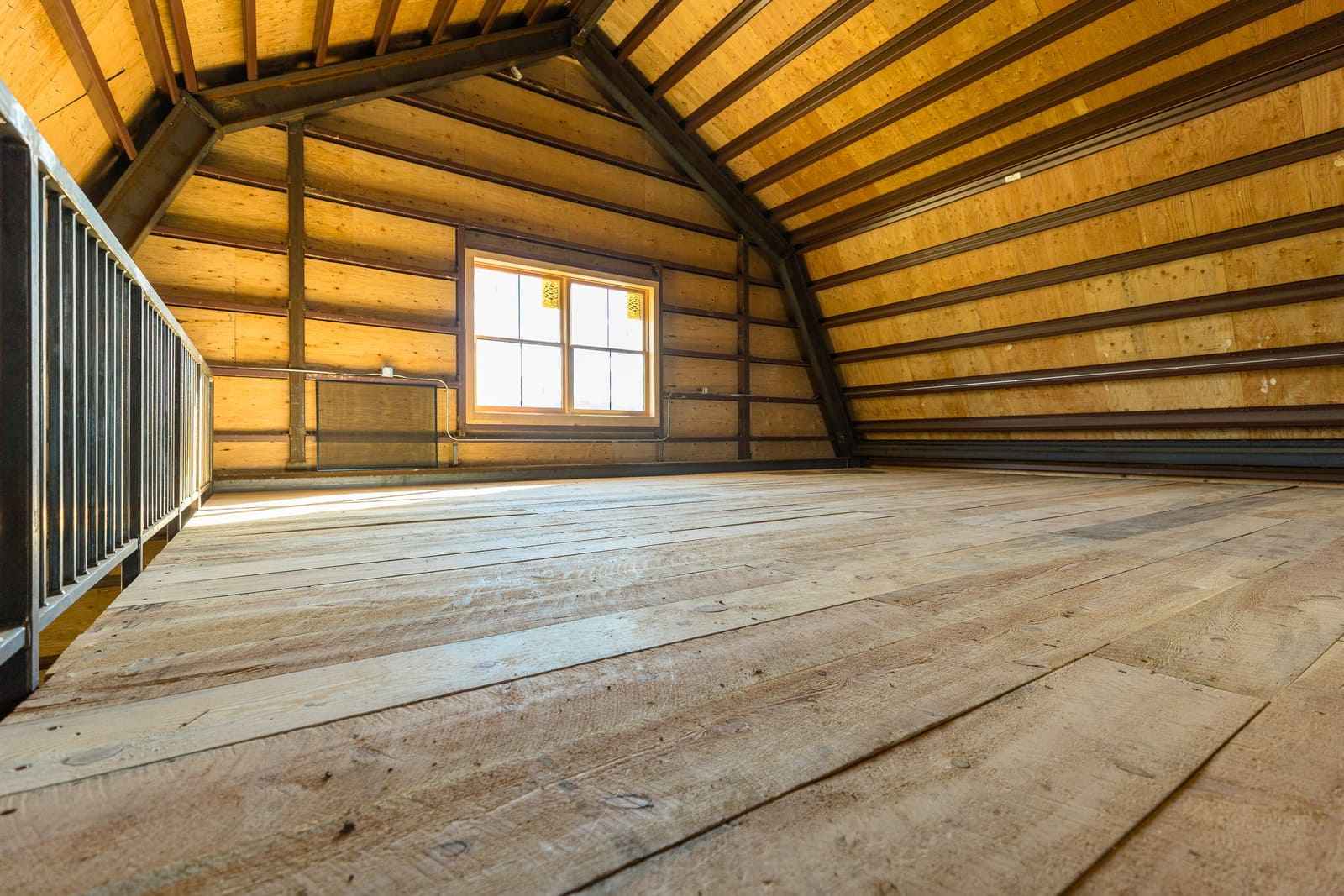 Upper level of barn interior with window and railing